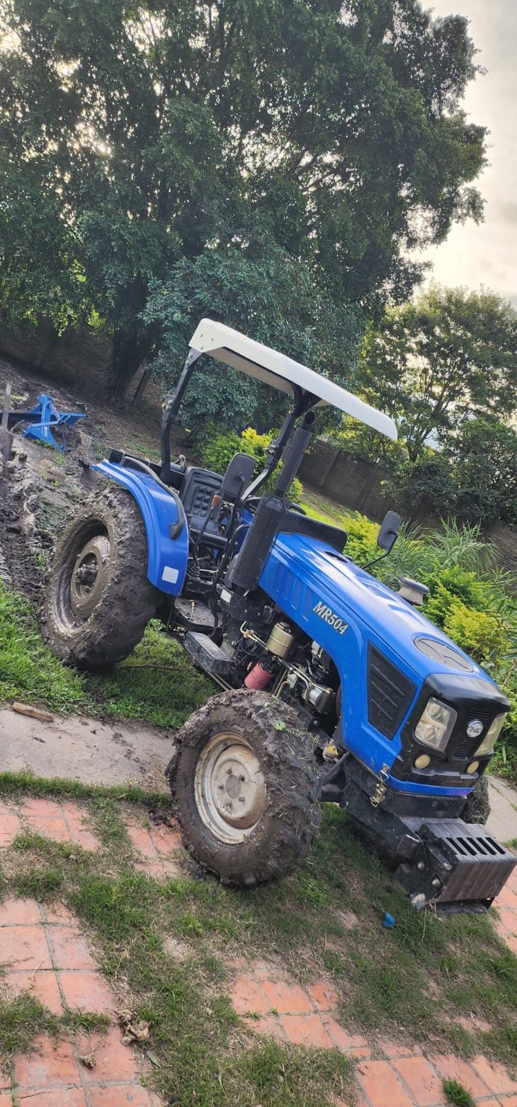 El tractor trabajando en un terreno recién desmontado, rodeado de palmeras
